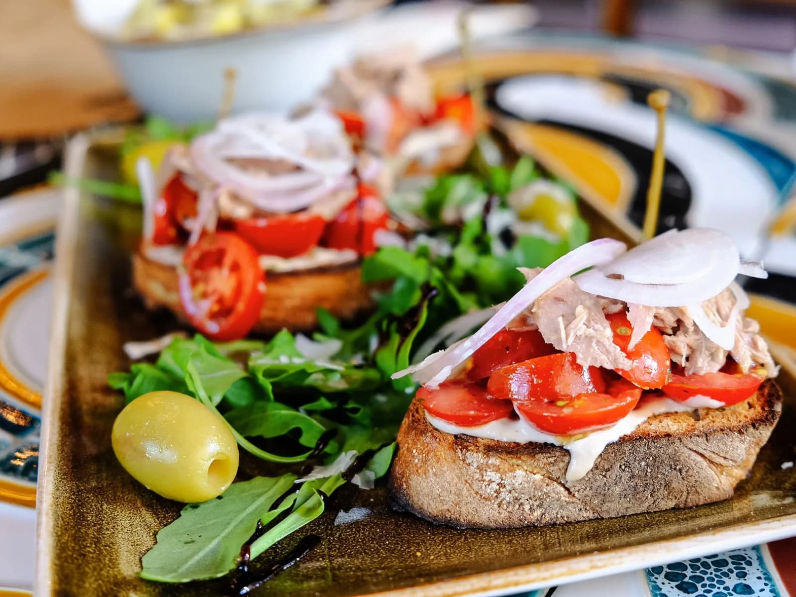 Röstbrot mit Tomaten, Rucola und Zwiebeln auf einem Teller
