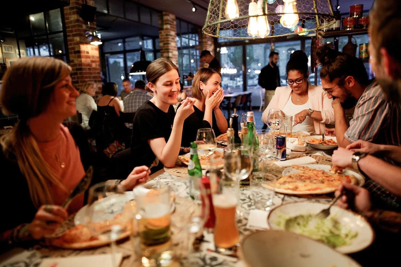 Große Runde am Tisch bei remos, Pizza und Wein zwischen lachenden Gästen